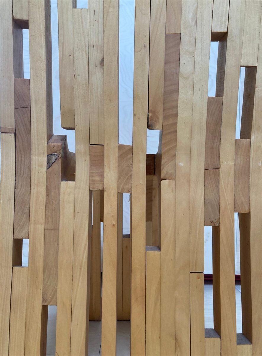 Detail of the back: vertical wooden slats of differing length and colour, with narrow openings between them letting the light through.