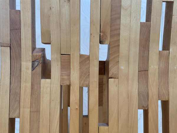 Detail van de rugleuning van de Extrude Chair: verticale houten latjes van verschillende lengte en kleur, met smalle openingen ertussen.