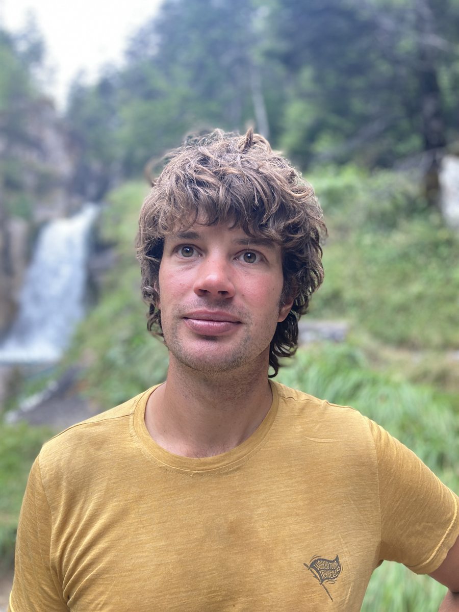 Ruben Dahmen buiten in een groen dal, met een waterval op de achtergrond.